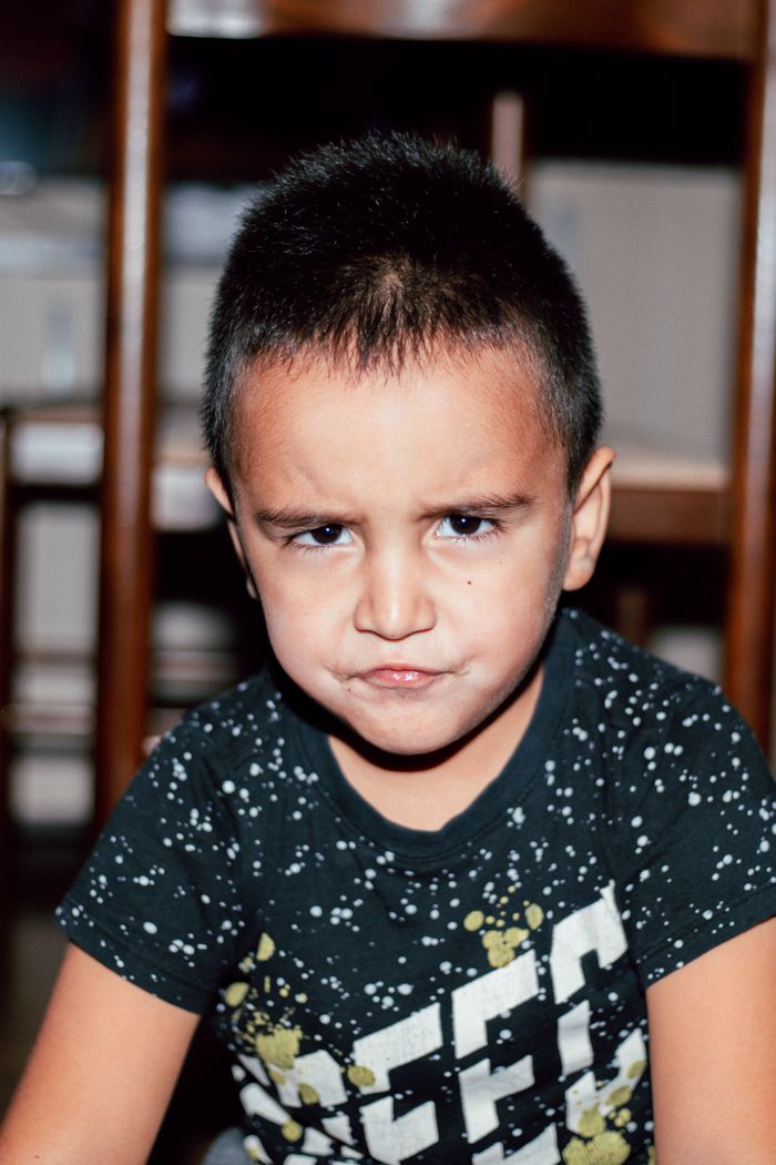 Young boy with serious expression indoors, conveying emotion.