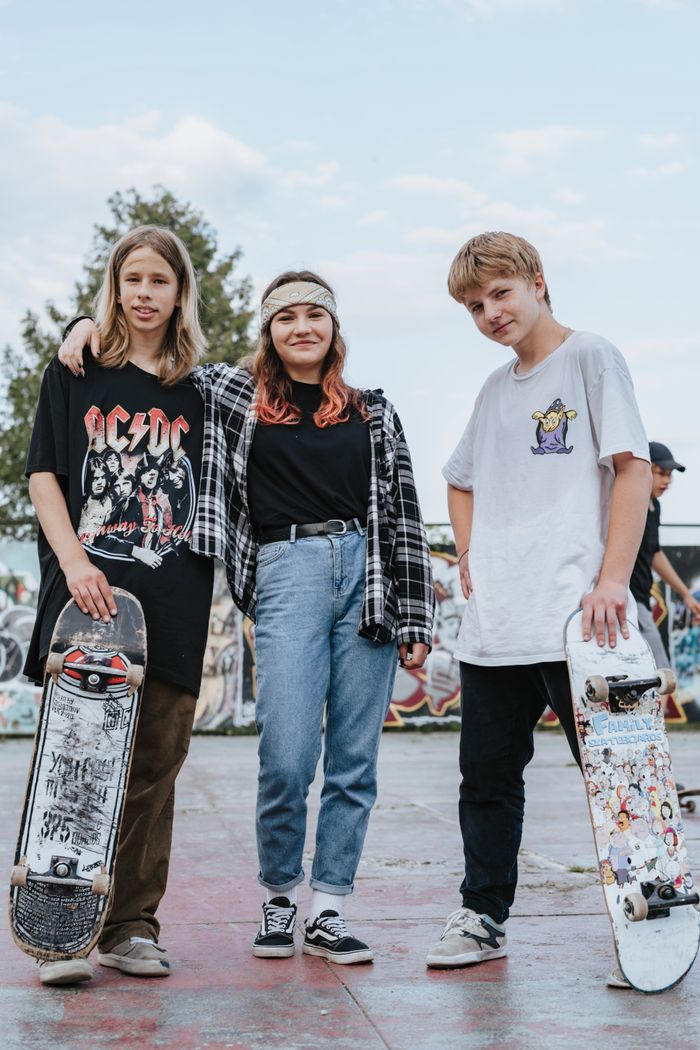 Three teenagers with skateboards posing confidently in a vibrant urban skatepark.