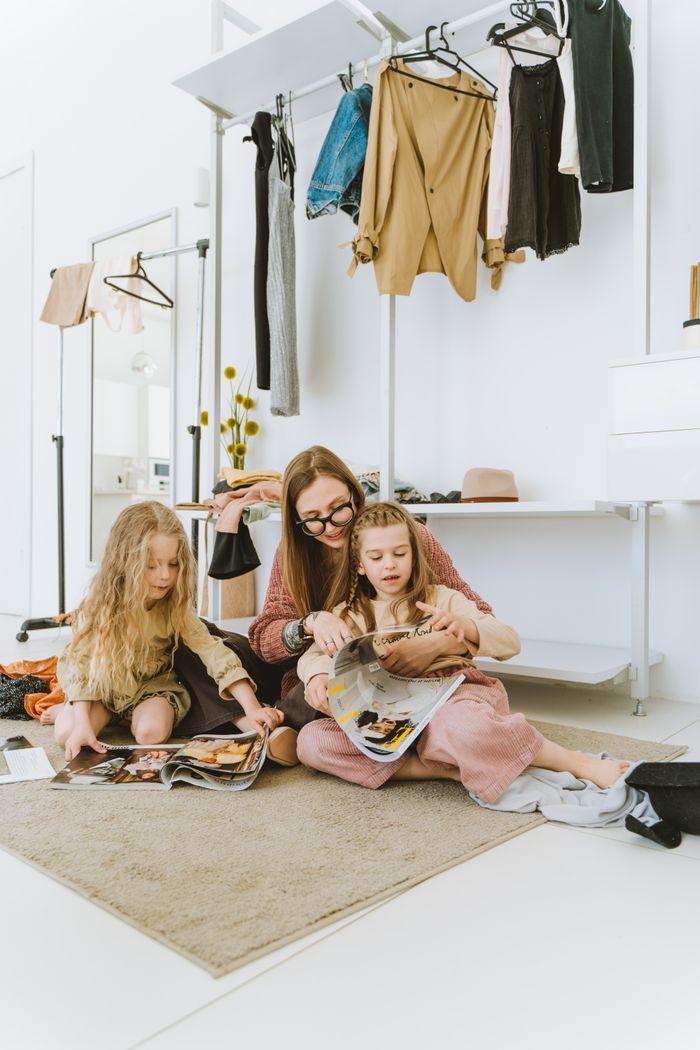 Mother and daughters enjoying magazines in a stylish wardrobe room setting.
